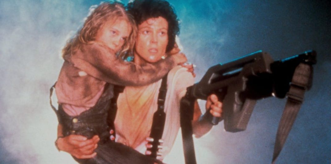 Ripley carrying Newt as she wields a gun