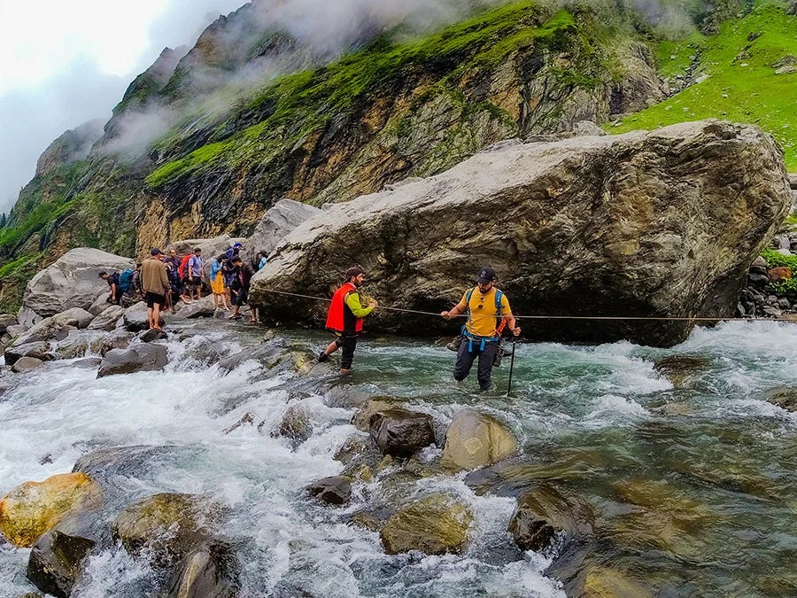 Trekkers crossing a river on Hampta Pass Trek
