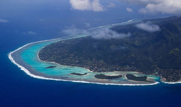 A bird’s eye view of an island. The water around has at least three different shades.