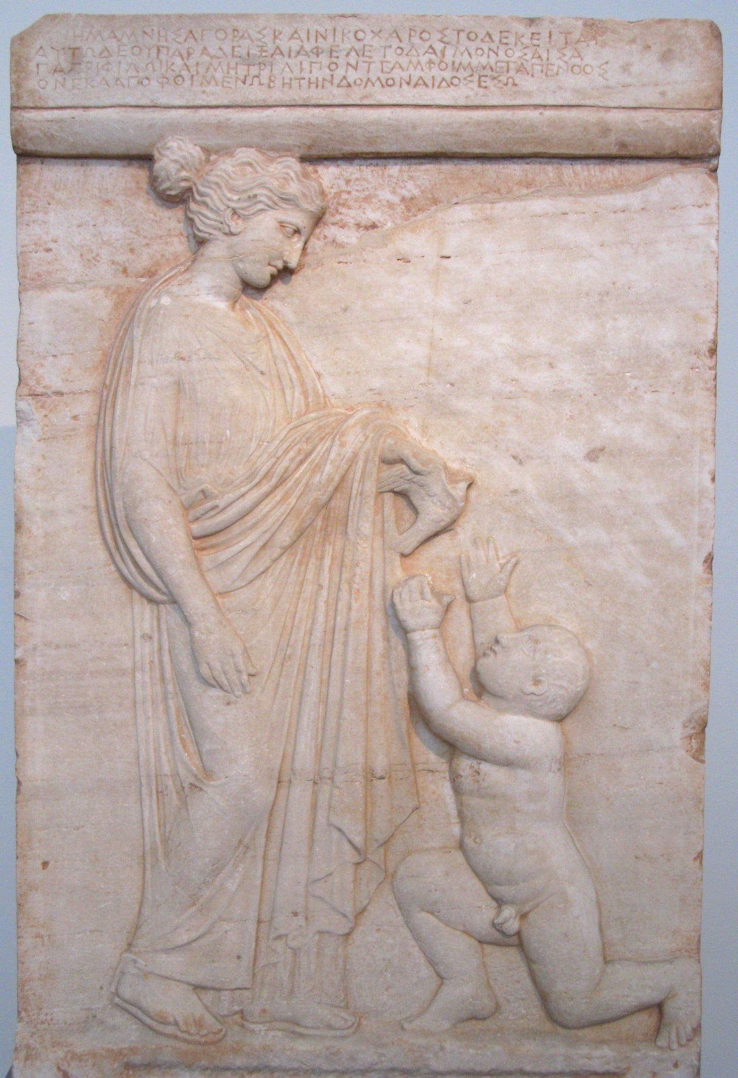 A marble stele with inscription on top section and a young woman and a small boy on the main part