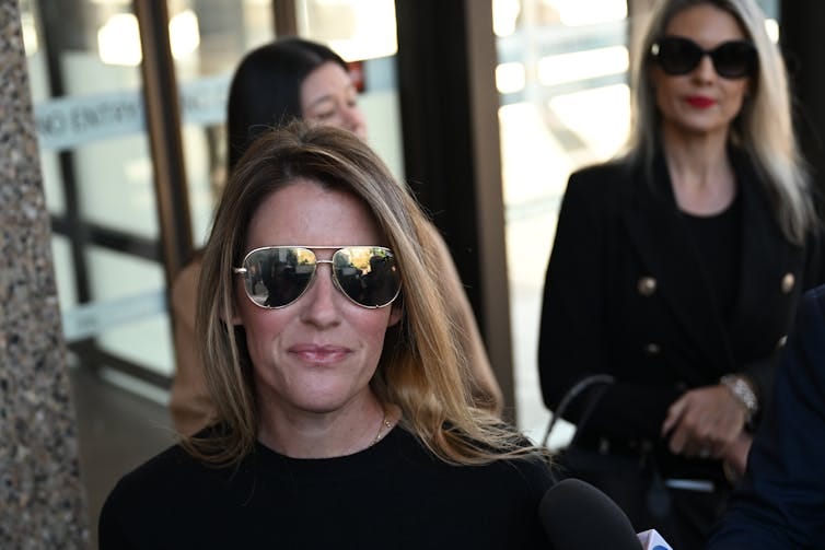 A woman wears mirrored aviator sunglasses outside court