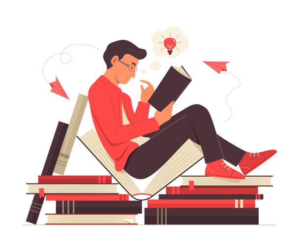 man sitting & reading on a pile of large books