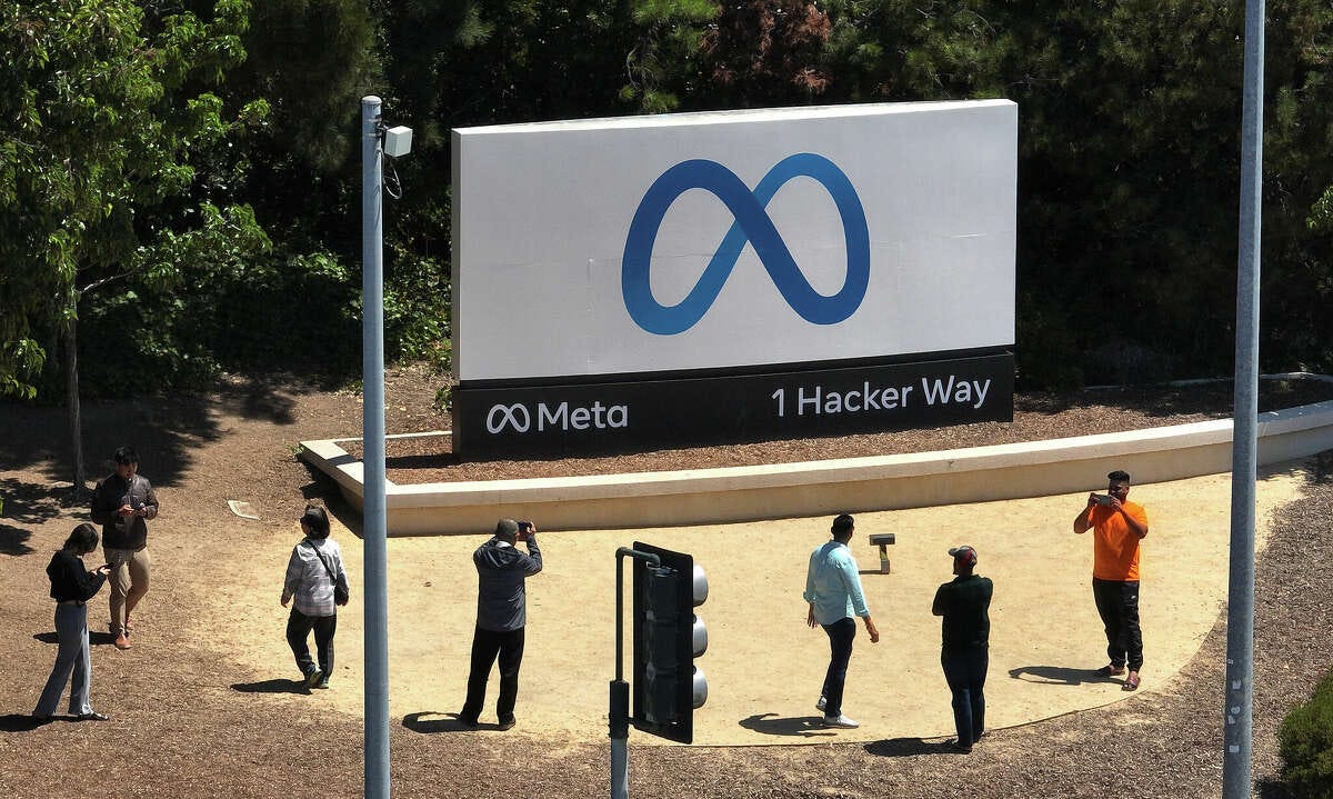 In an aerial view, people gather in front of a sign posted at Meta headquarters on July 7, 2023, in Menlo Park, Calif. Meta announced last quarter's earnings on Wednesday.