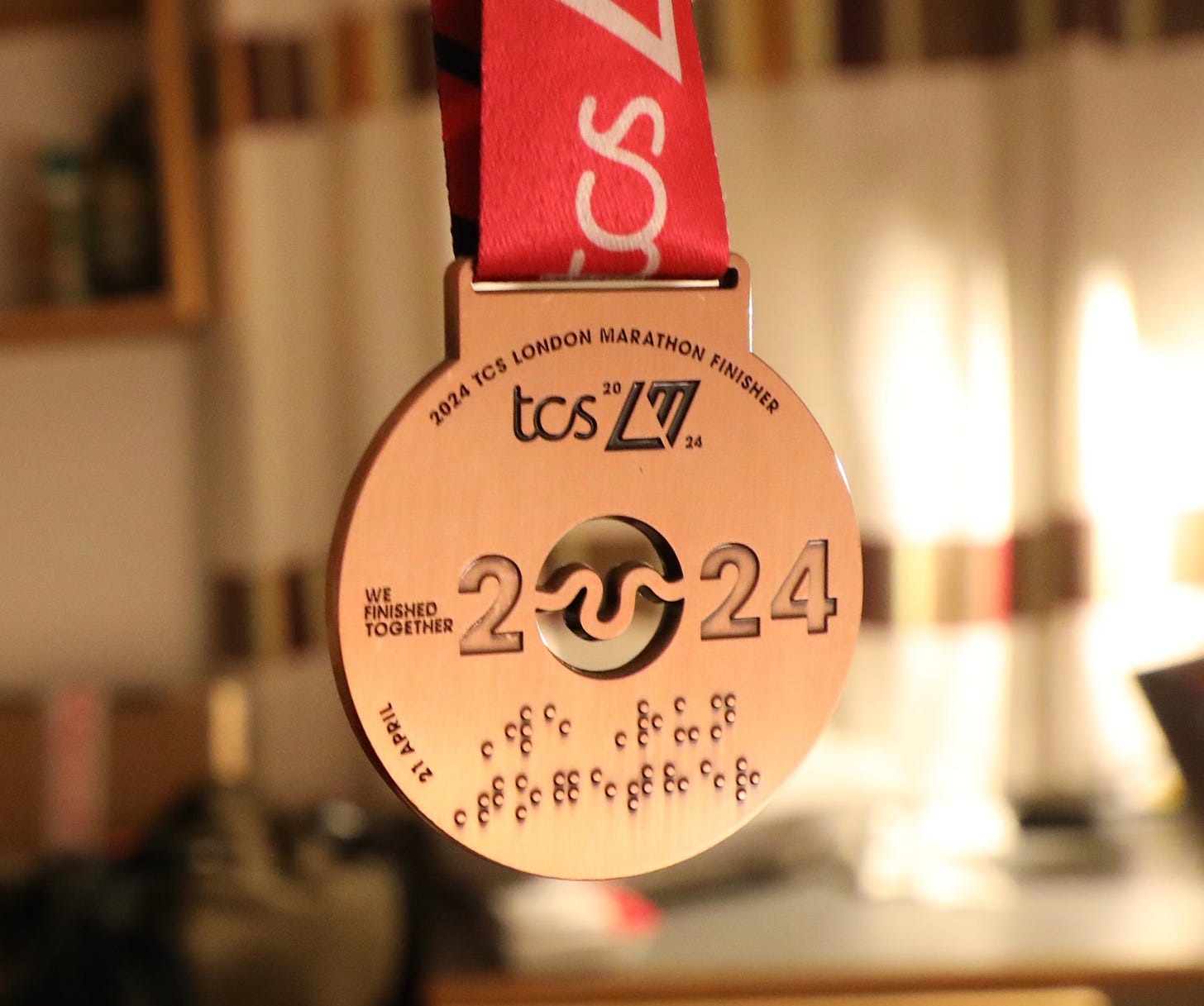 A close up photo of the race medal which has braille at the bottom.