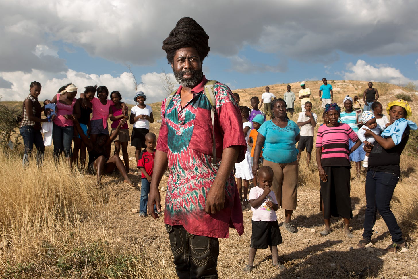 Augustin Mona stands on land near the Village Grace de Dieu in Canaan with some of the 126 families who had been together since meeting in the Mozayik tent camp after the 2010 earthquake, Jan. 10, 2015.