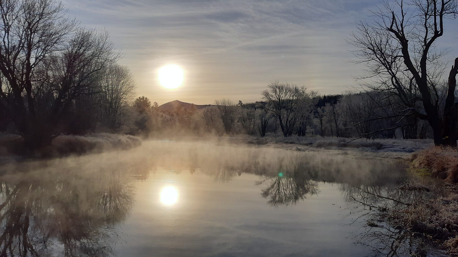 sun rises over Saranac River with frost on trees