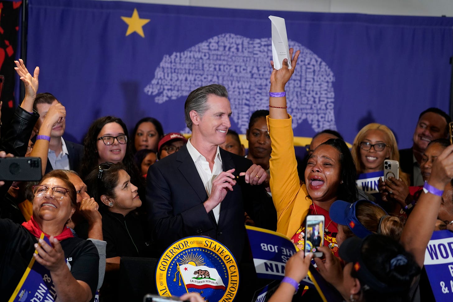 California Gov. Gavin Newsom signs the fast food bill surrounded by cheering fast food workers at the SEIU Local 721 in Los Angeles.