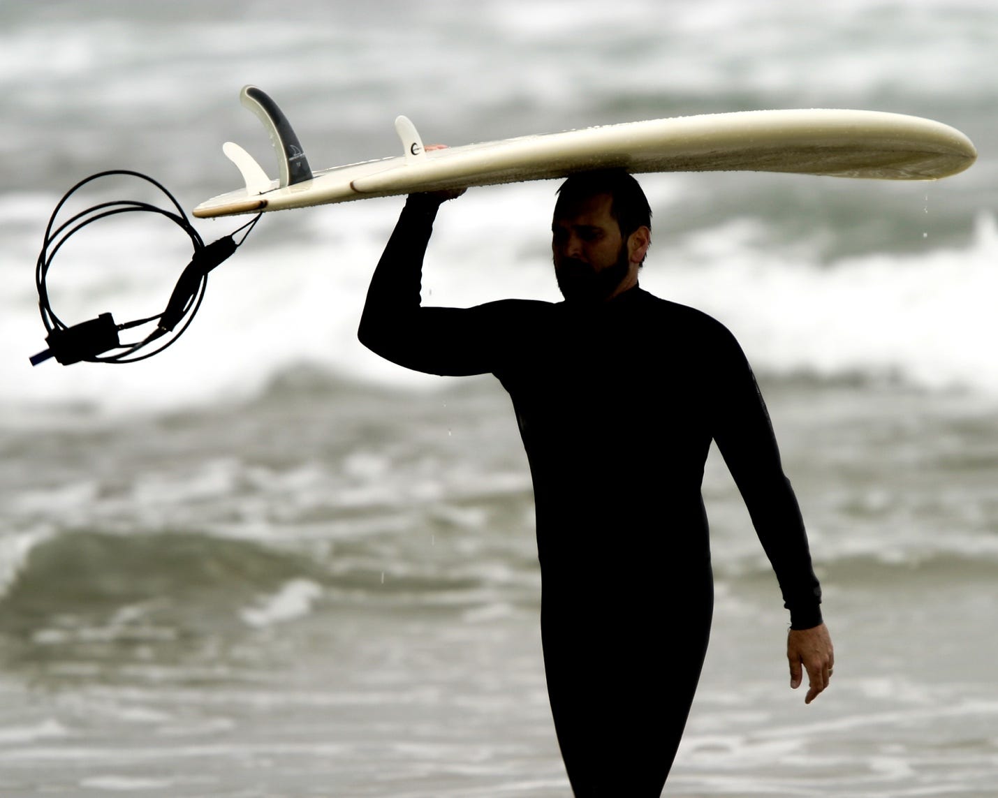 A person carrying a surfboard over his head

Description automatically generated