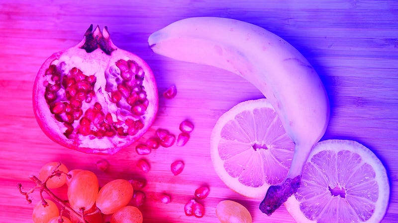 An image of a banana, slices of lemon, pomegranate and grapes.