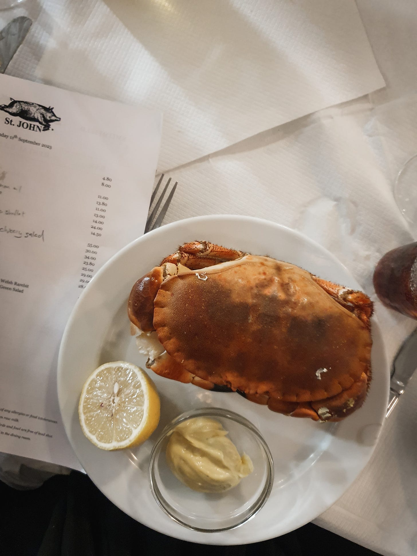 Photo of a whole crab on a plate on a table with white tablecloths