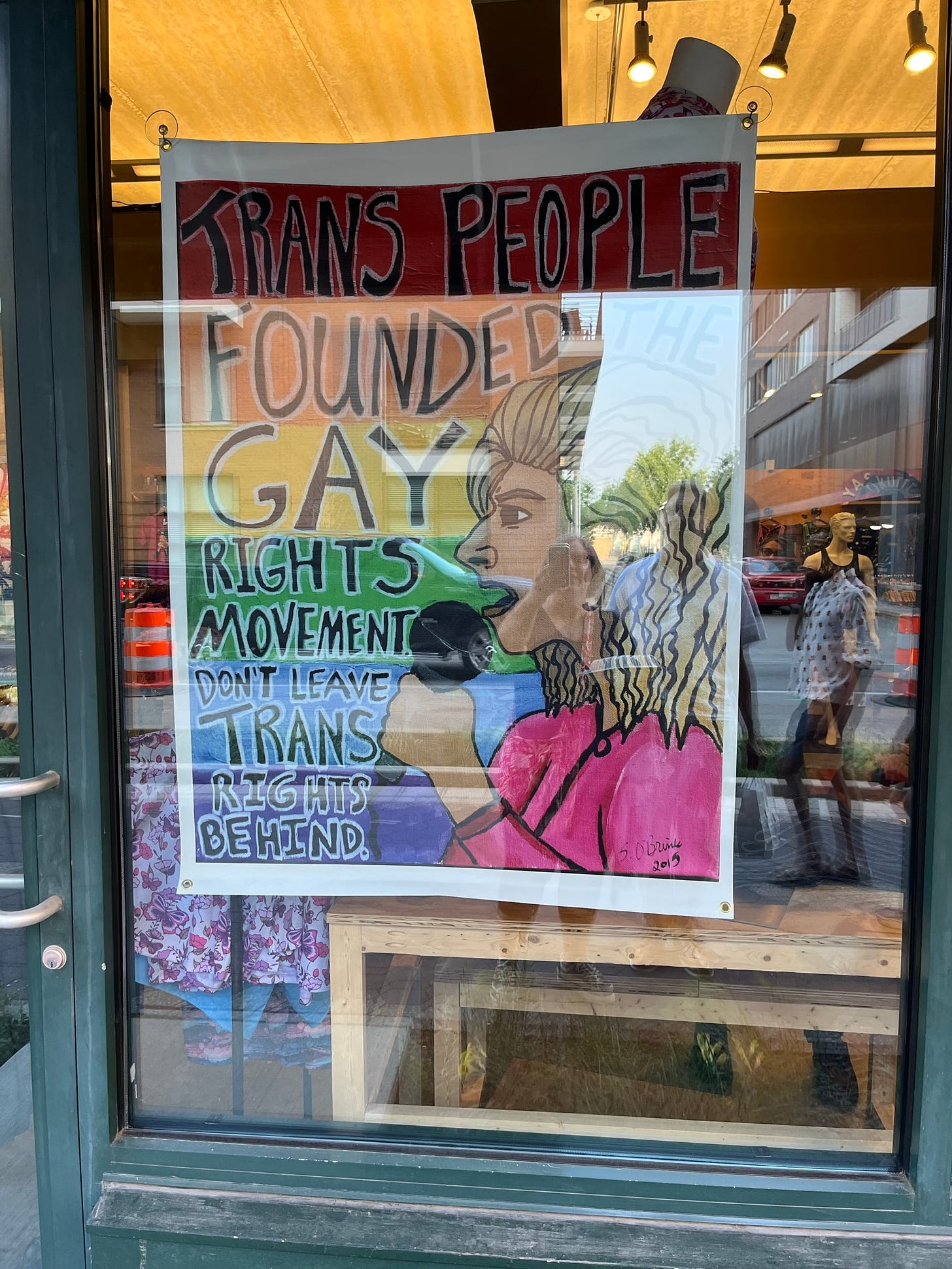 Sign in a shop window that says, "Trans people founded gay rights movement. Don't leave them behind."