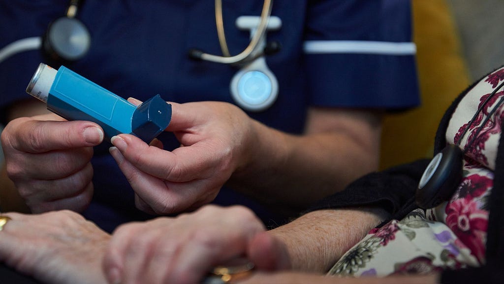 A doctor showing an asthma inhaler to a patient