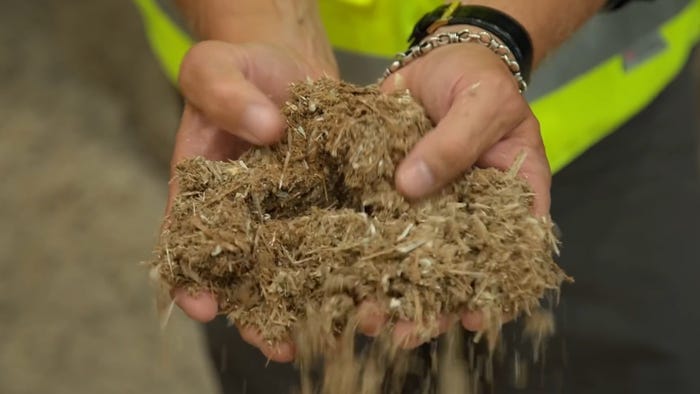 Closeup of two hands holding brown shredded material.