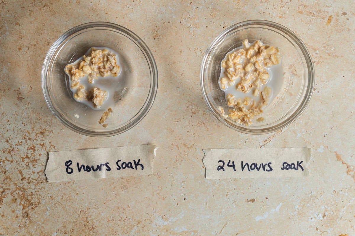 Two bowls of soaked, uncooked oats on a countertop demonstrating the difference between an 8 hour soak and a 24 hour soak.