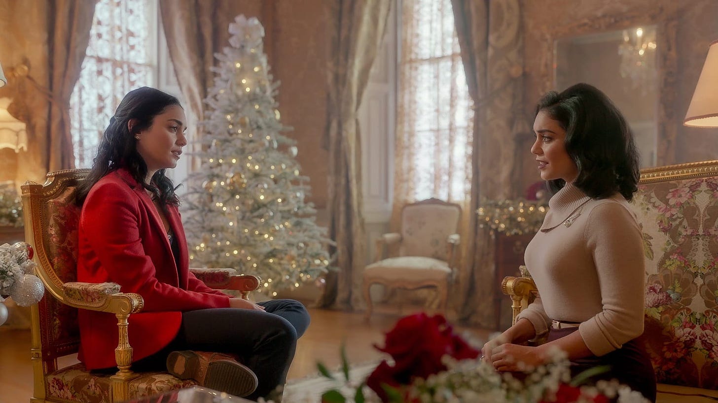 Movie still from The Princess Switch: Switched Again. Two identical Vanessa Hudgens characters chat in an elegant living room, decorated with a Christmas tree.