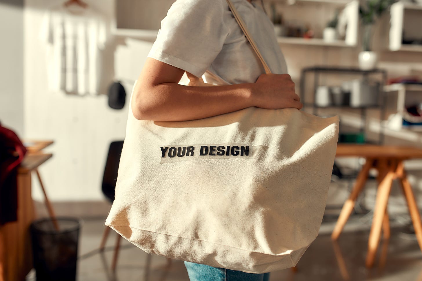 A white woman holding a canvas bag that reads "Your Design".