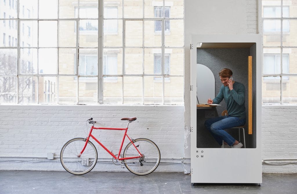 Man in a tiny workspace room beside a bicycle