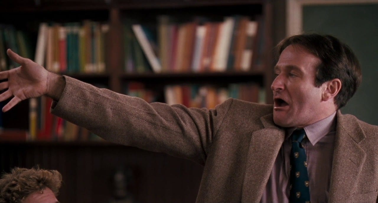 Robin Williams in Dead Poet's Society mugging ferociously while reading poetry.