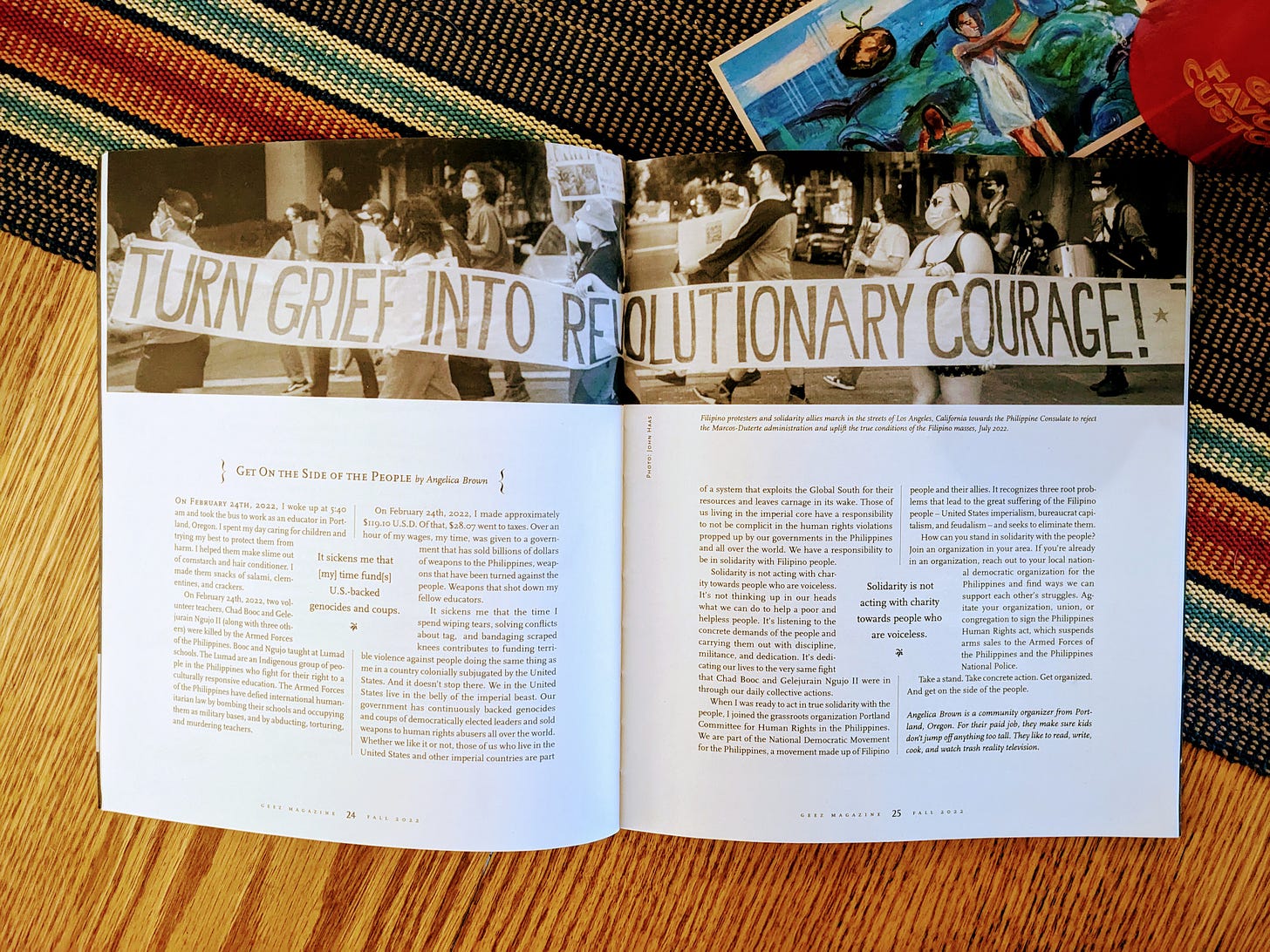 A magazine open on a table, with a photo of people carrying a banner that reads: "Turn grief into revolutionary courage!"