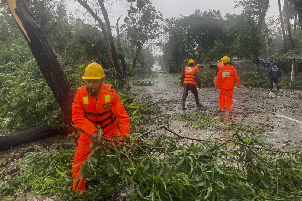 Rescue workers remove the fallen tress after a storm in Teknaf, near Cox's Bazar, Bangladesh, Sunday, May 14, 2023. Bangladesh and Myanmar braced Sunday as a severe cyclone started to hit coastal areas and authorities urged thousands of people in both countries to seek shelter. (AP Photo/Al-emrun Garjon)