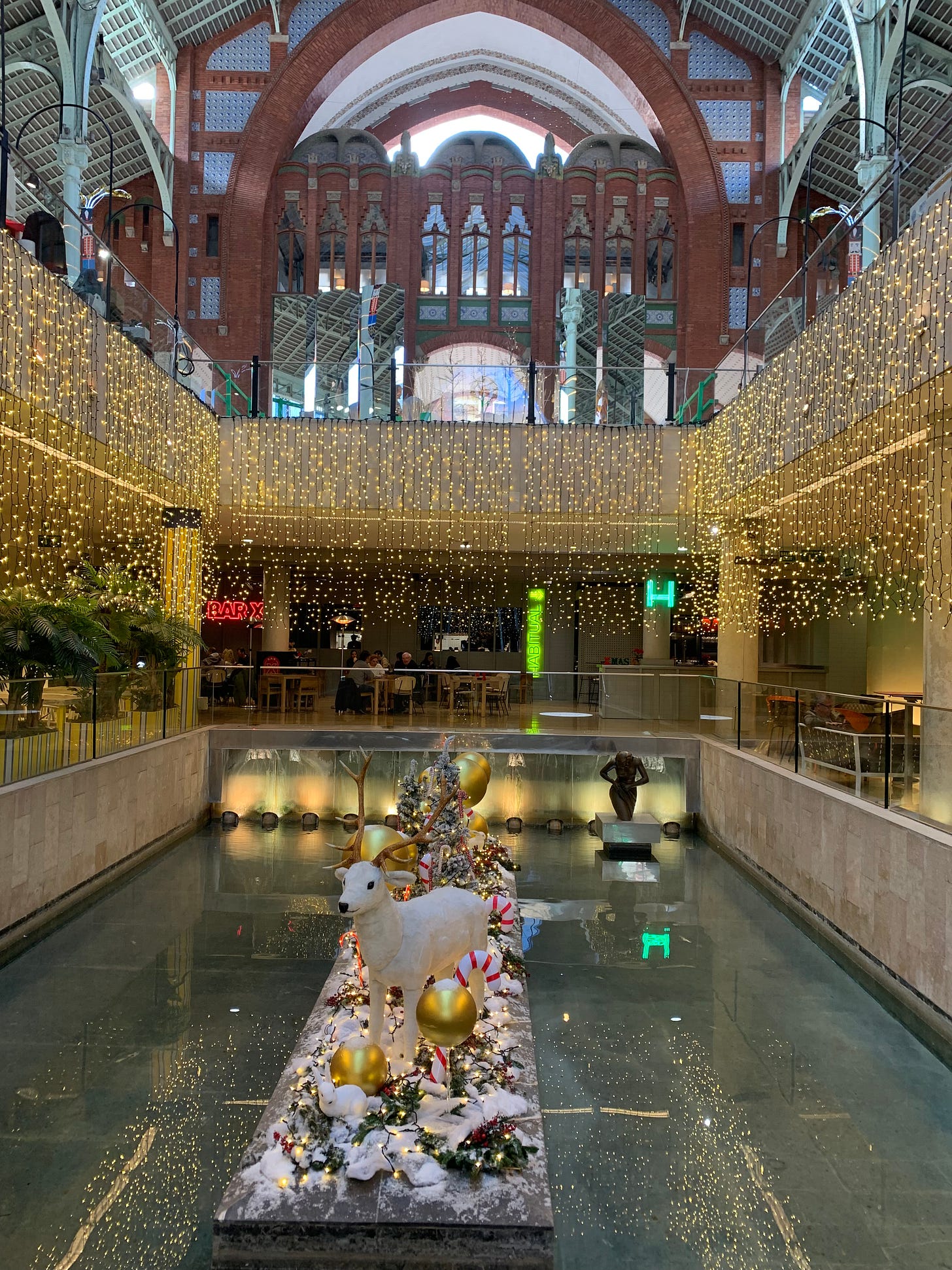 The lower level of Colon Market has curtains of lights hanging around the central decorative pool and in the center is a Christmas scene with reindeer and other festive decorations.