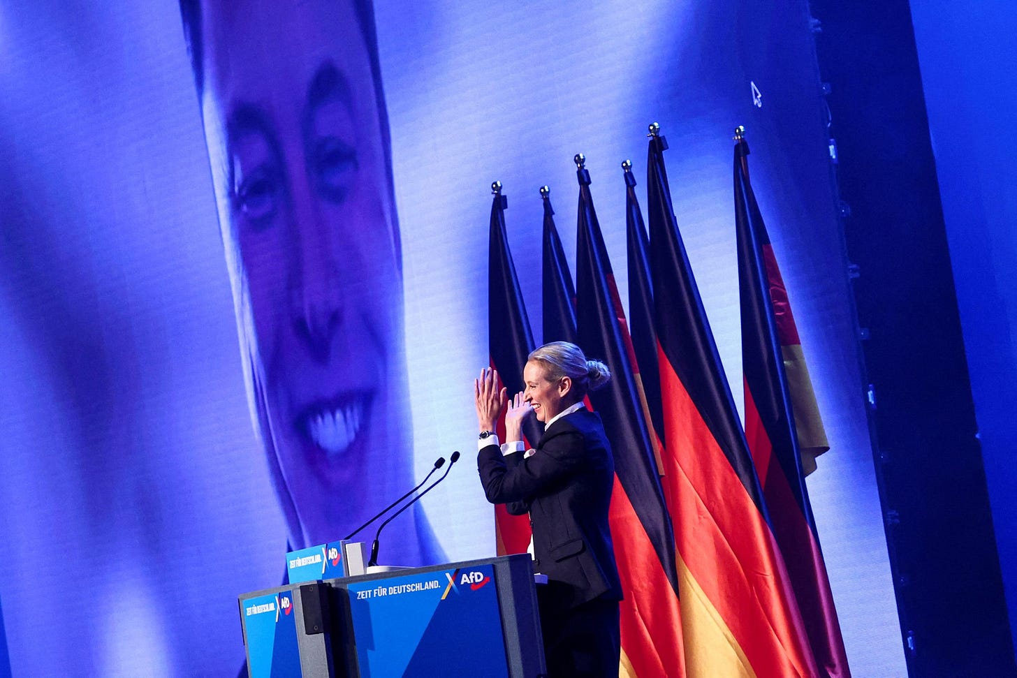 Alice Weidel, co-leader of the Alternative for Germany party (AfD), claps as SpaceX CEO Elon Musk is seen on screen during a central election campaign event of the AfD in Halle (Saale), Germany, January 25, 2025. REUTERS/Karina Hessland