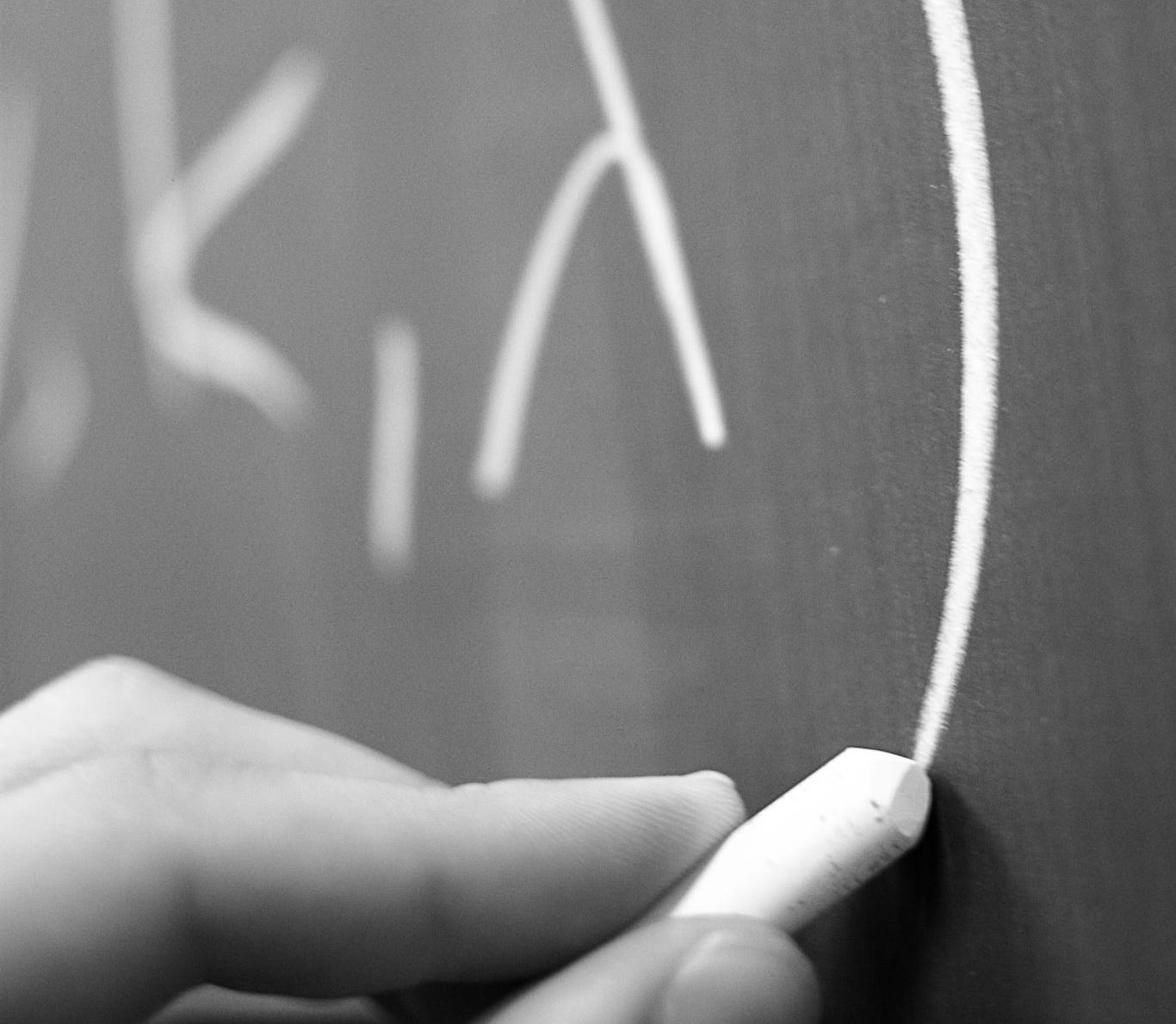 A hand writing on a chalkboard with chalk