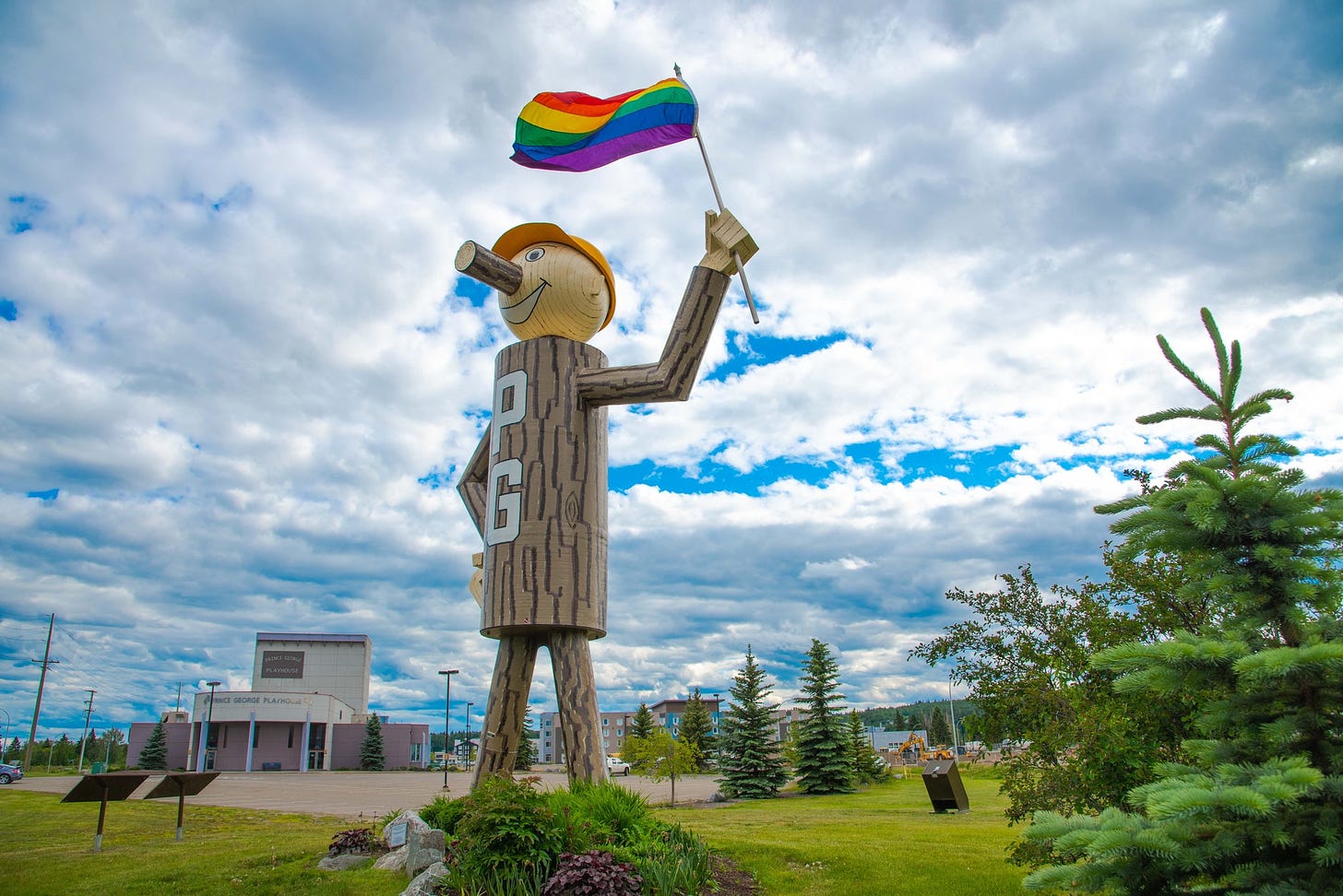 Mr. PG holding a pride flag on a cloudy summer afternoon