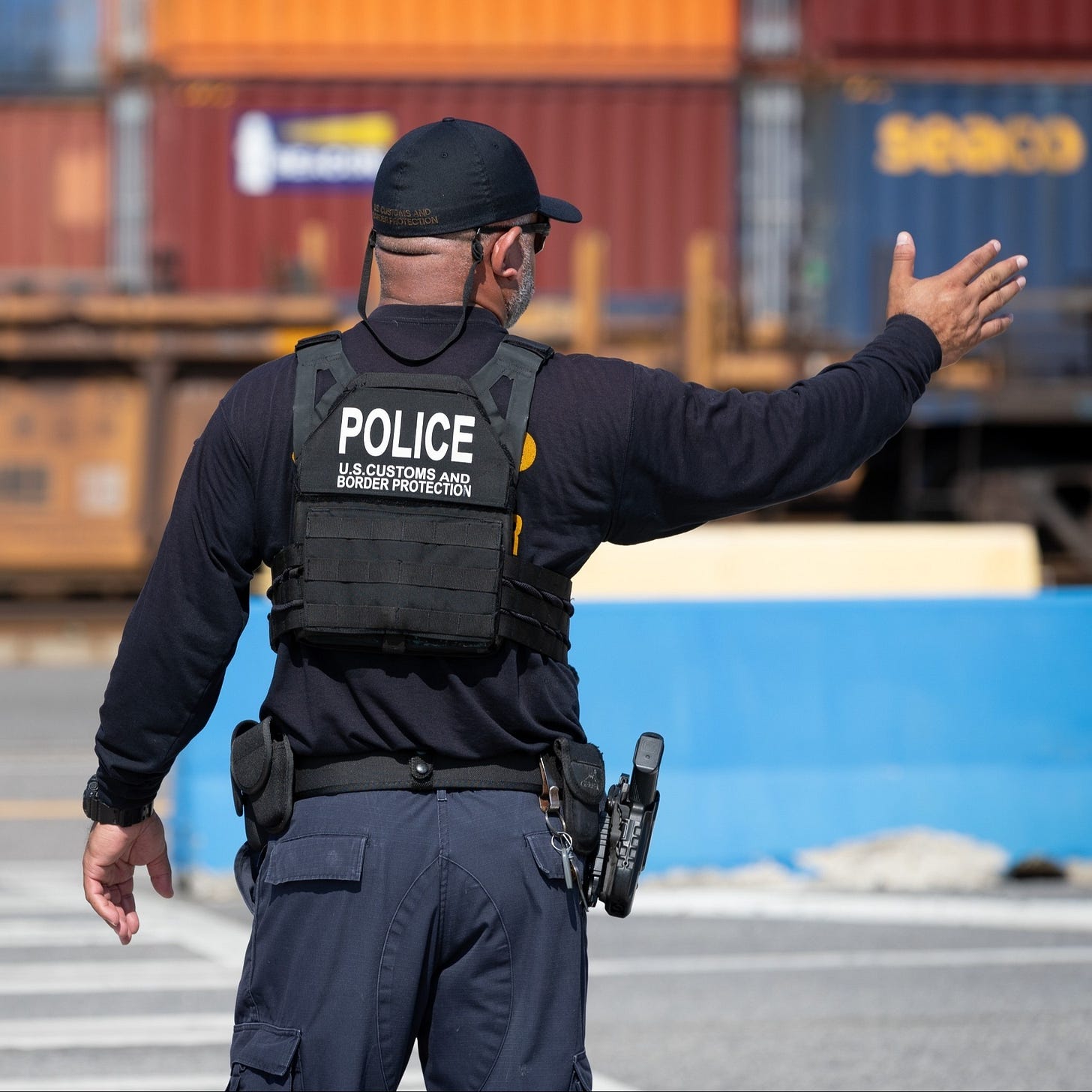 A CBP officer directs foreign cargo arriving at a US Port of Entry toward an area where it can be examined for compliance with US laws. A CBP officer directs foreign cargo arriving at a US Port of Entry toward an area where it can be examined for compliance with US laws.