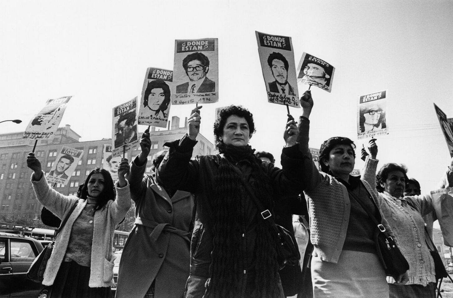 May be a black-and-white image of 7 people, people standing, poster, banner, crowd and text
