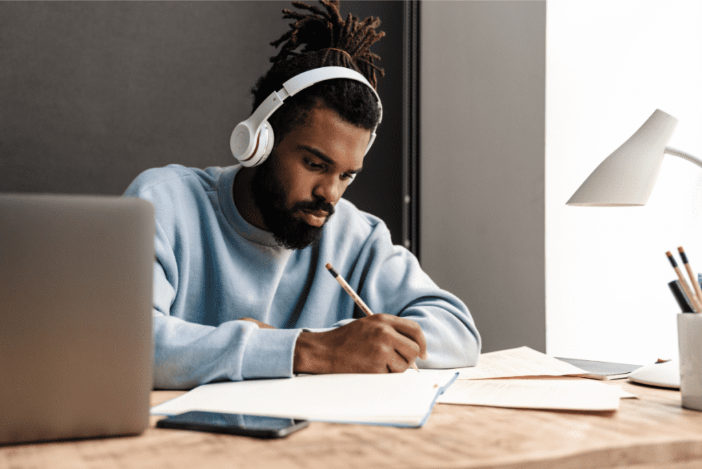 young man working at desk wearing headphones ambient music for focus, productivity, and distraction free environment