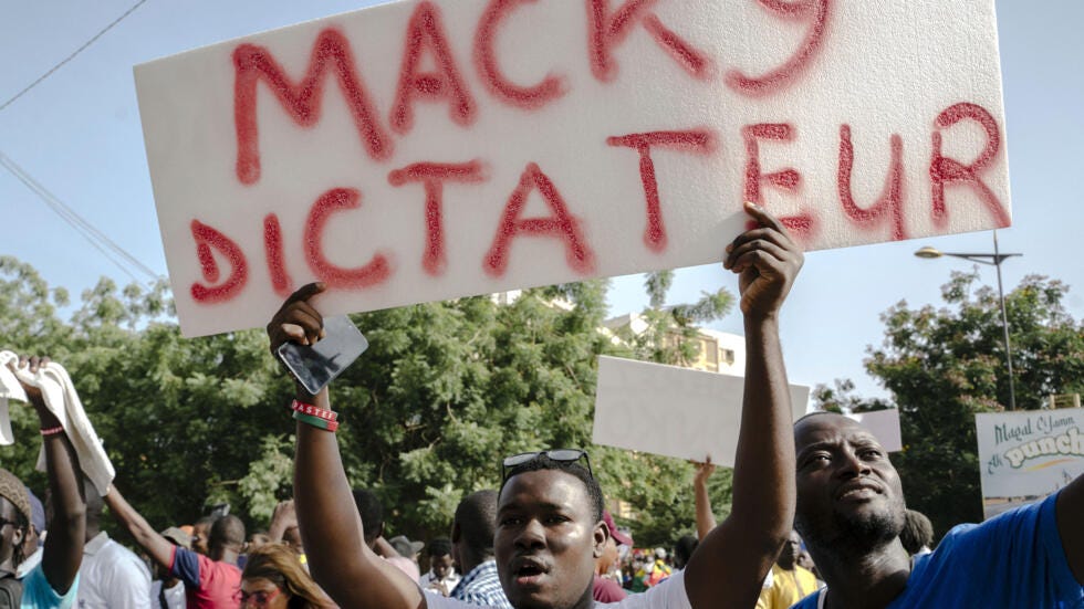 A demonstrator holds a placard reading "Macky dictator" during a rally called by Senegal's new opposition coalition "F24 Movement of Vital Forces" to demand the release of detained Senegalese opposition leader Ousmane Sonko and all political prisoners in Dakar, on 27 October 2023.