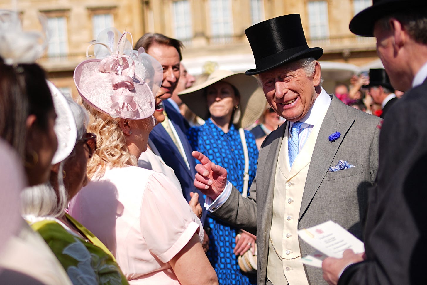 King Charles smiling with guests at Buckingham Palace