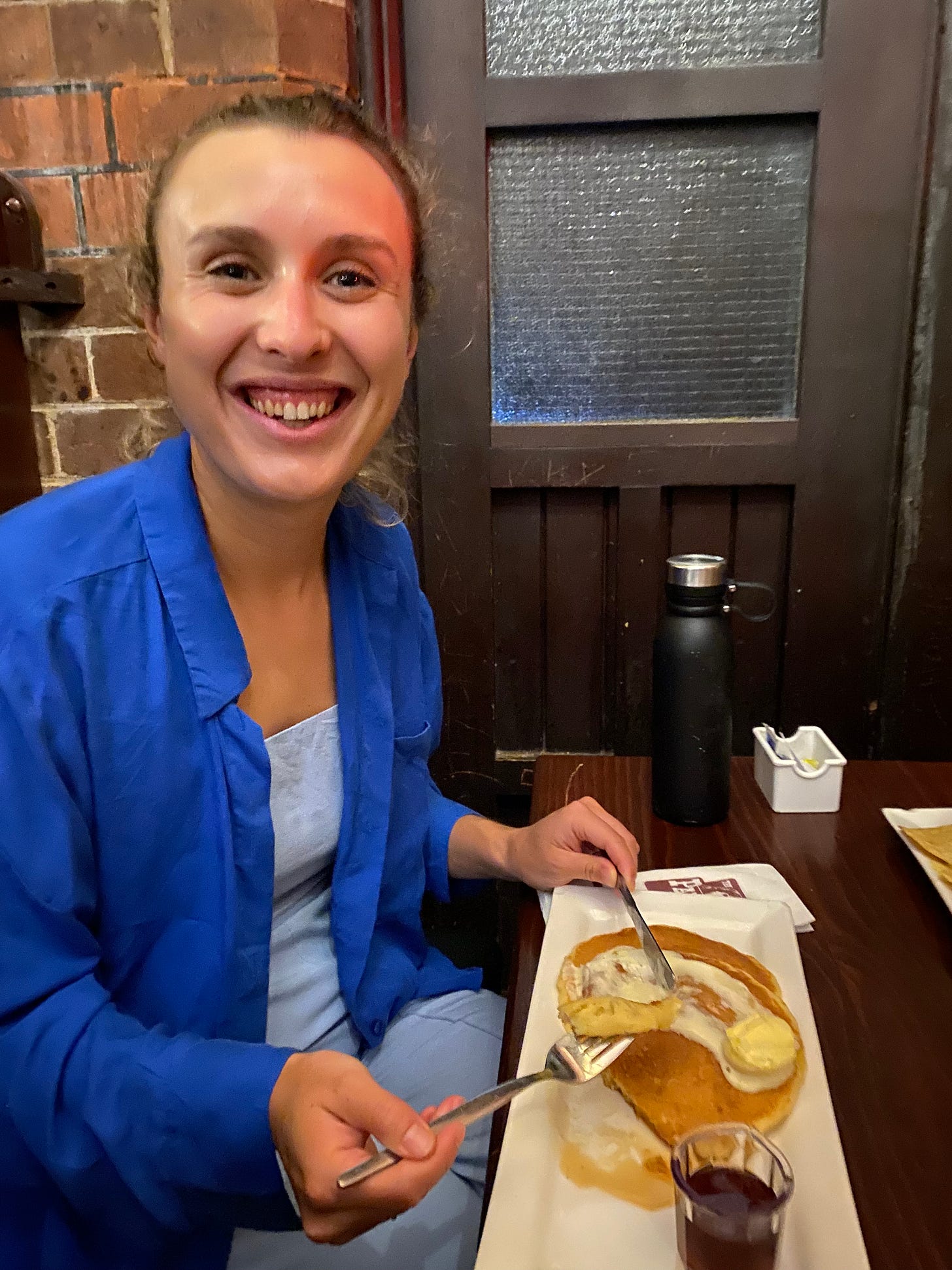 Author smiling while eating pancakes