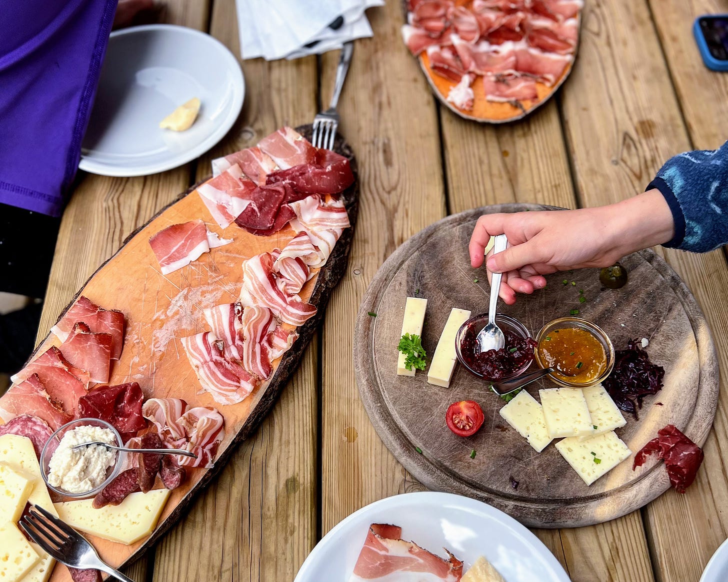 Charcuterie board with a hand spooning jam onto bread from the board