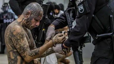 Reuters A prison agent guards a gang member as he is processed at his arrival after 2000 gang members were transferred to the Terrorism Confinement Center,