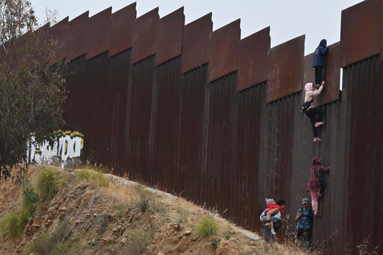 A group of adult and child migrants are smuggled at the Tijuana-San Diego border, as they climb the wall to seek asylum to the United States in Tijuana, Baja California, Mexico, on June 7, 2024. Anadolu via Getty Images