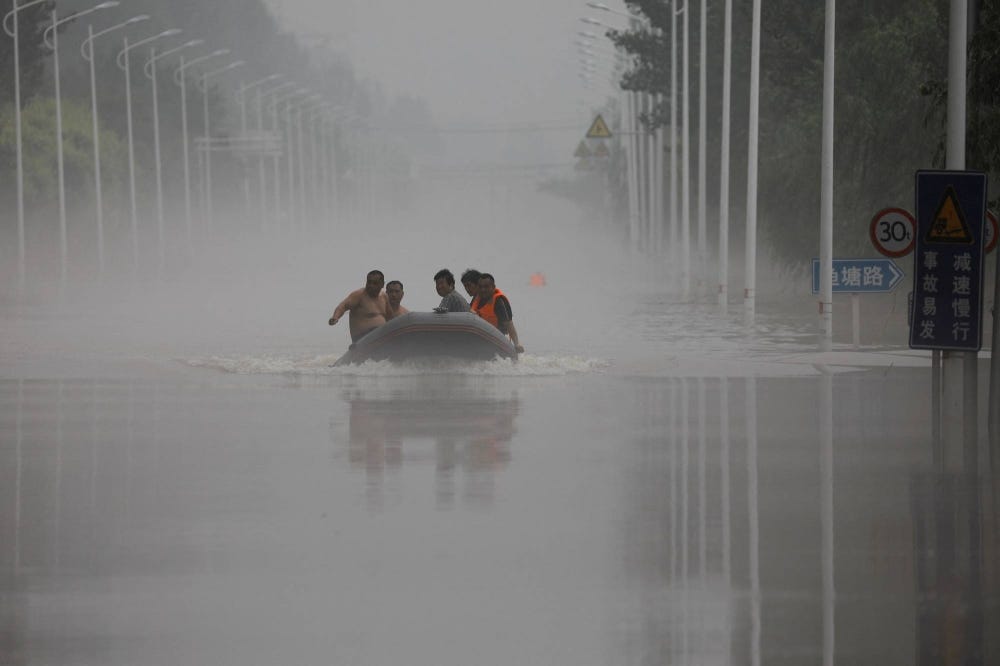 Five men in an inflatable boat motoring down a street, now a river.