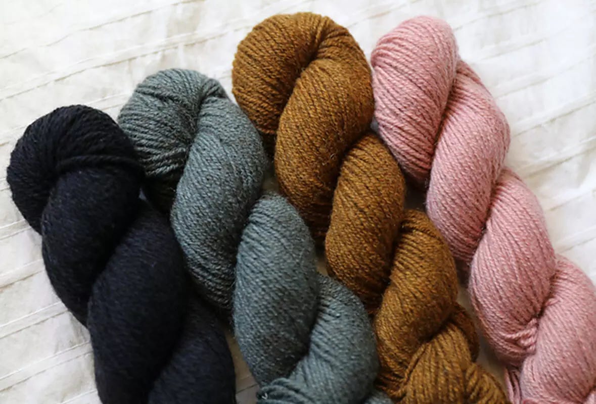 Four skeins of different colored yak yarn on a white background. 