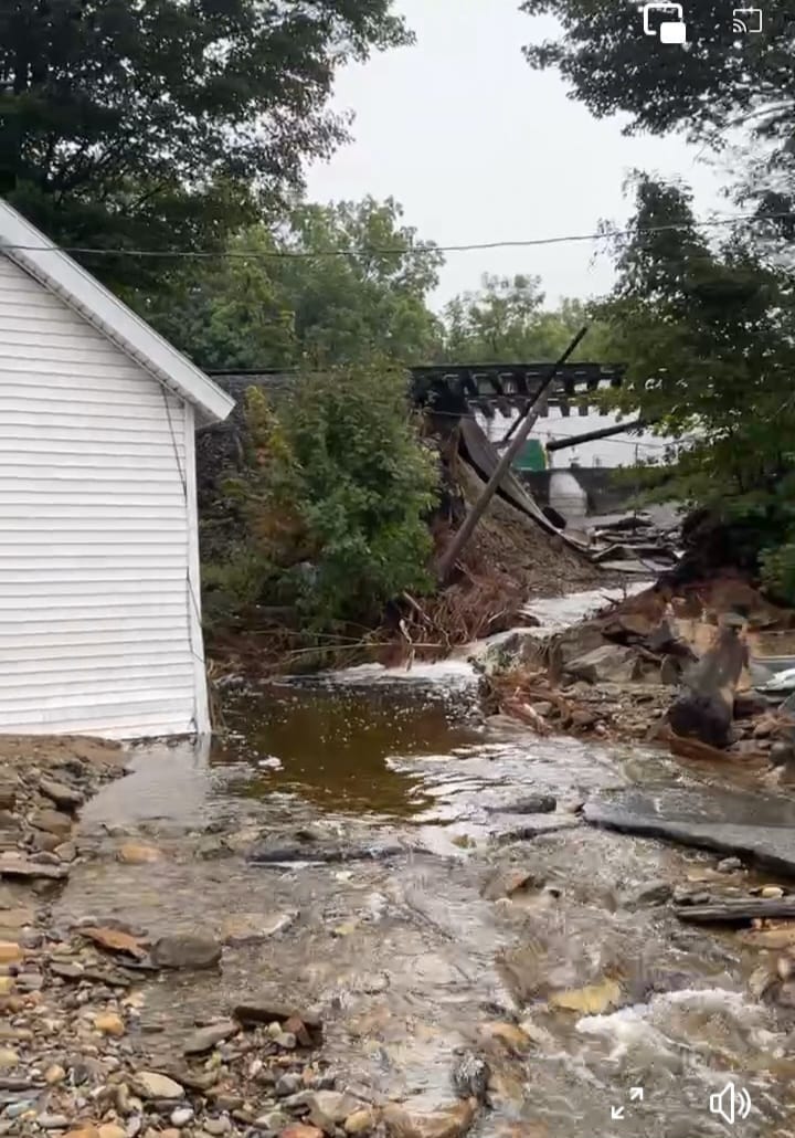 A damaged elevated train track over a flood/erosion zone in a citizen's yard in Fitchburg, Massachusetts