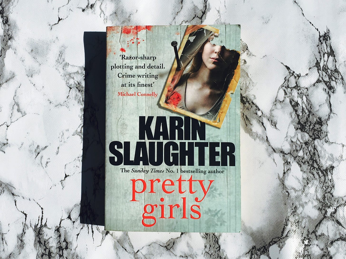 Pretty Girls by Karin Slaughter paperback book on a white marble effect background.