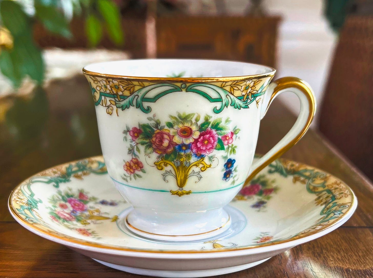 A gold-rimmed flowered demitasse tea cup and saucer 