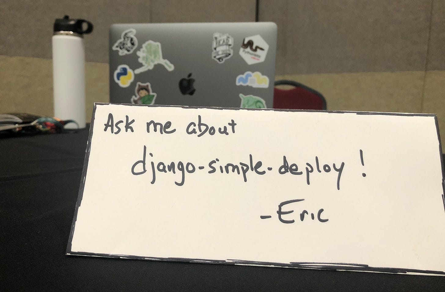 Placard on a tabletop reading "Ask me about django-simple-deploy!"
