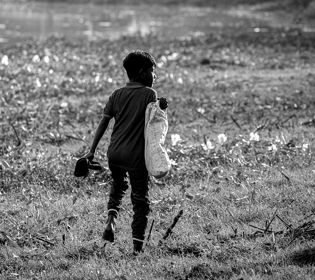 a young boy walking across a lush green field