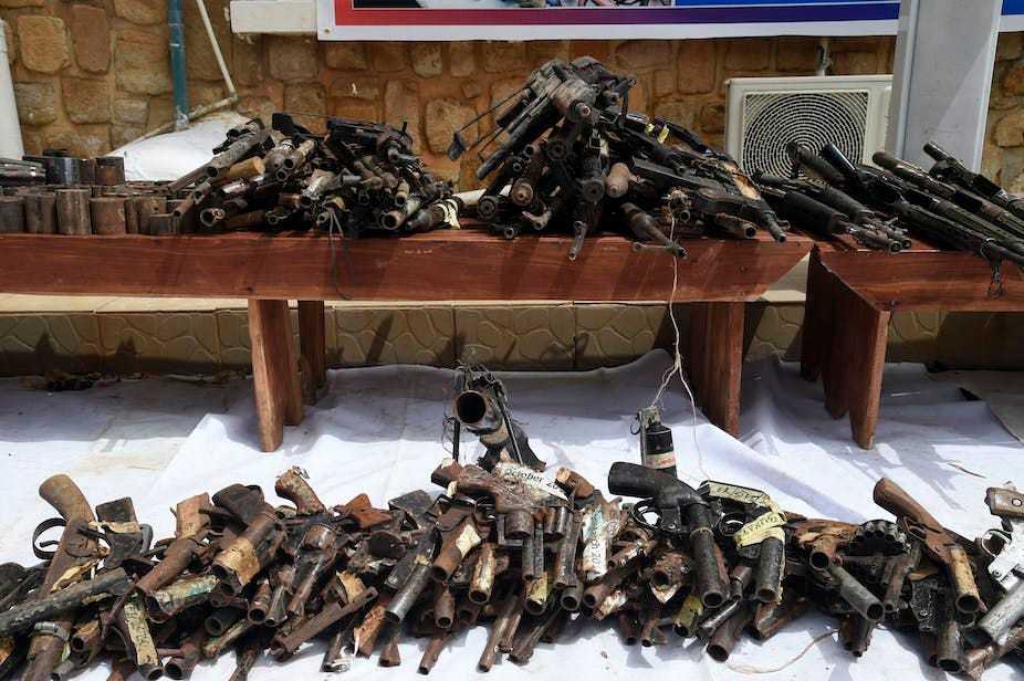 Several seized guns displayed on the floor and on tables.