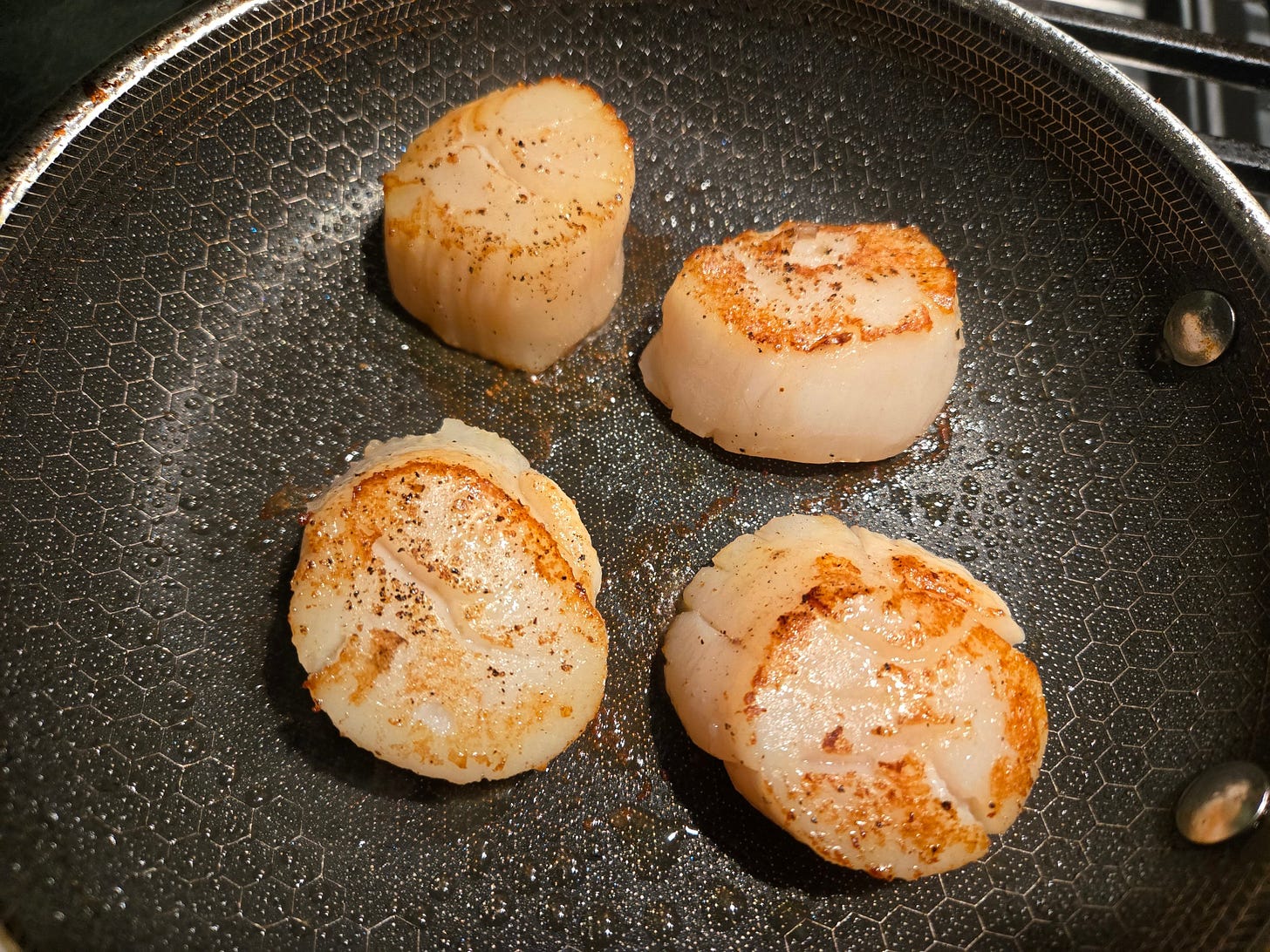 Seared scallops in a skillet.