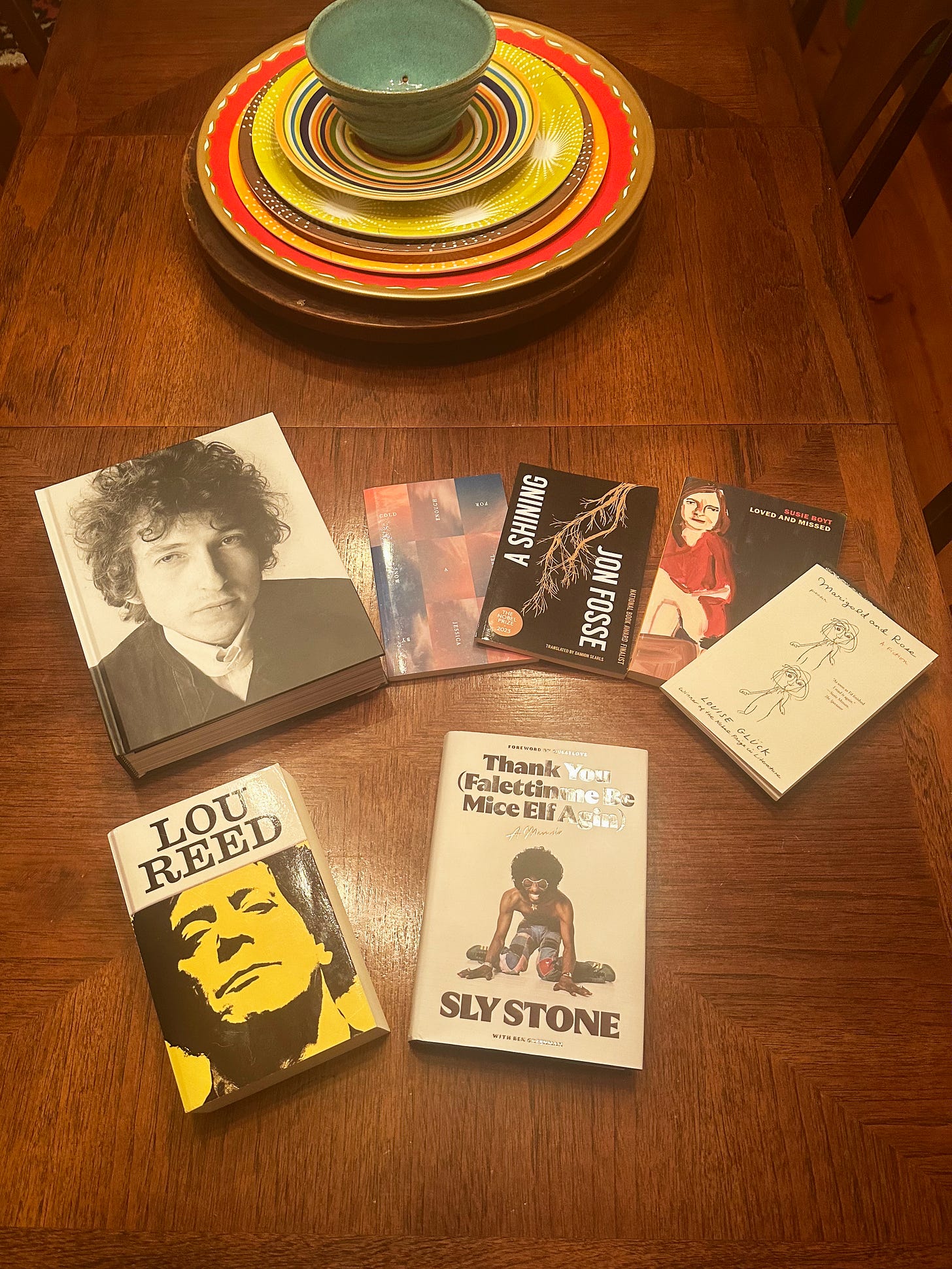 Several books laid out on a wooden table, with a colorful lazy Susan in the background.
