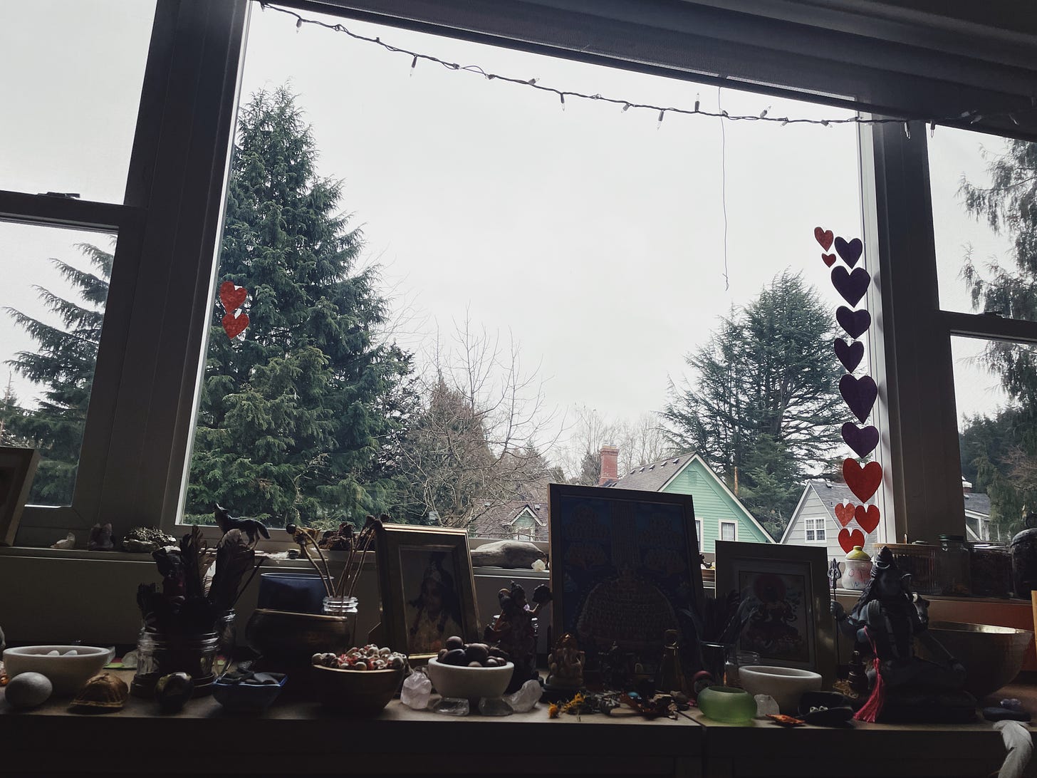 Altar of natural items and photos and hearts, trees and gray-white sky in the background