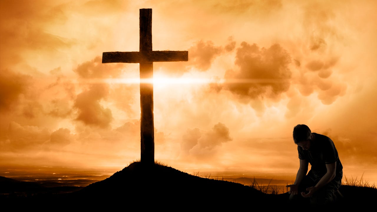 A man kneeling beside a cross.