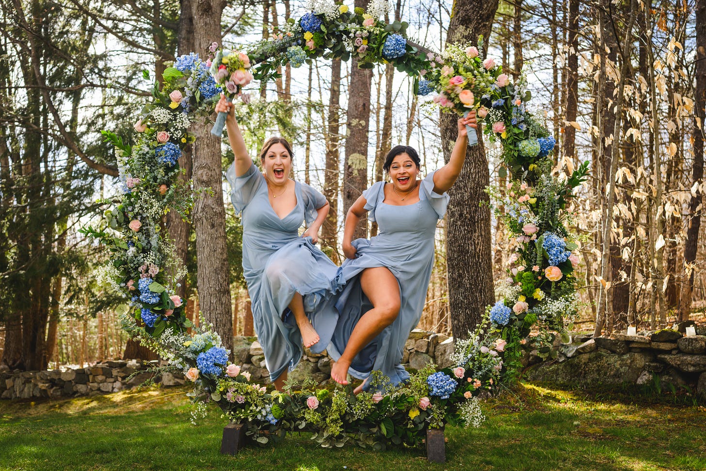 Two bridesmaids leaping through a circular arbor